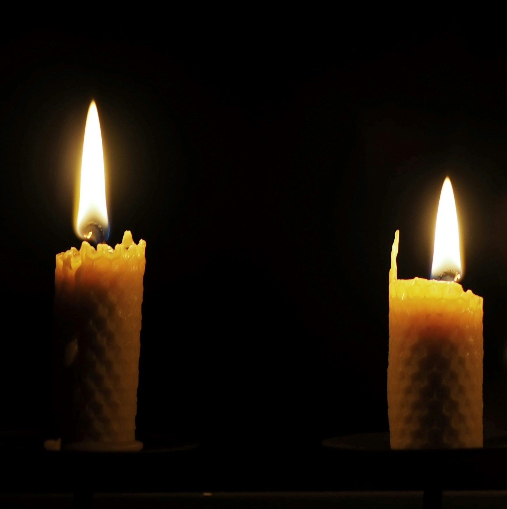 two lit beeswax tapers in a dark environment. Photo by Niklas Ohlrogge, 2018 https://unsplash.com/photos/four-yellow-scented-pillar-candles-i8RKD8wlMHI