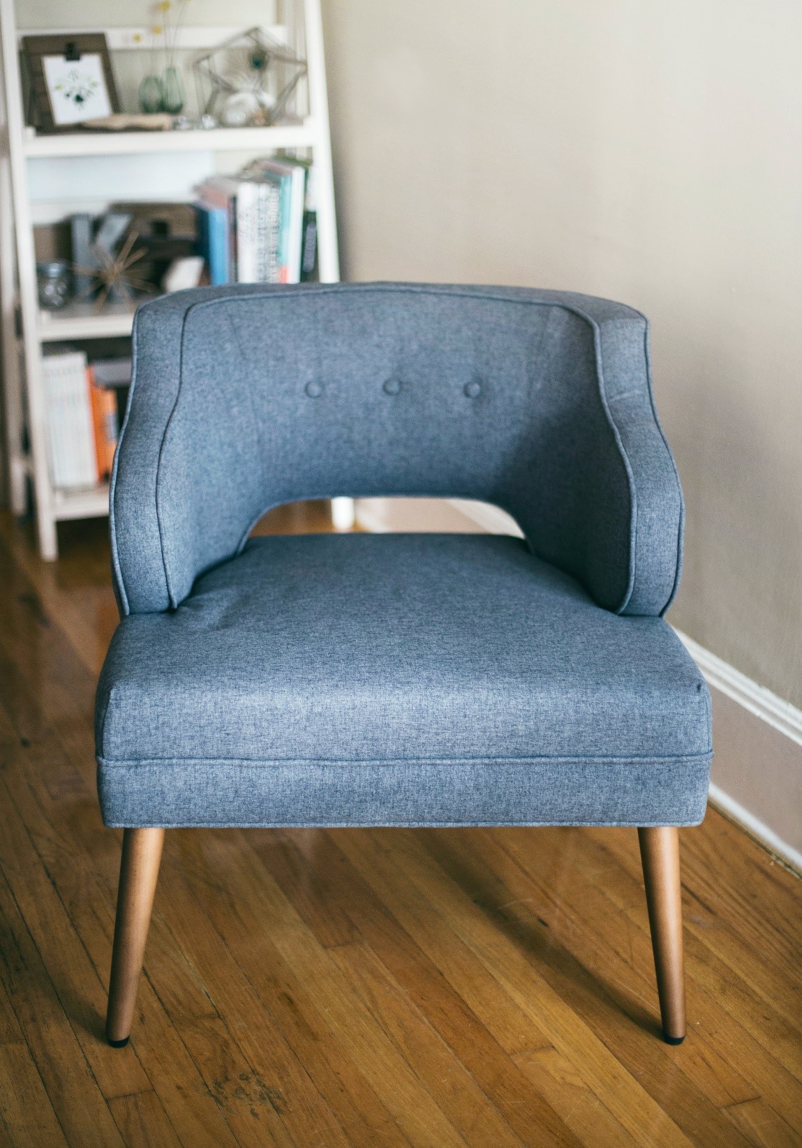 a blue cloth chair with a bookshelf out of focus behind it. Photo by Kari Shea, https://unsplash.com/photos/ItMggD0EguY