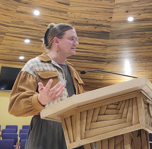 site author standing at a well-lit pulpit delivering a sermon